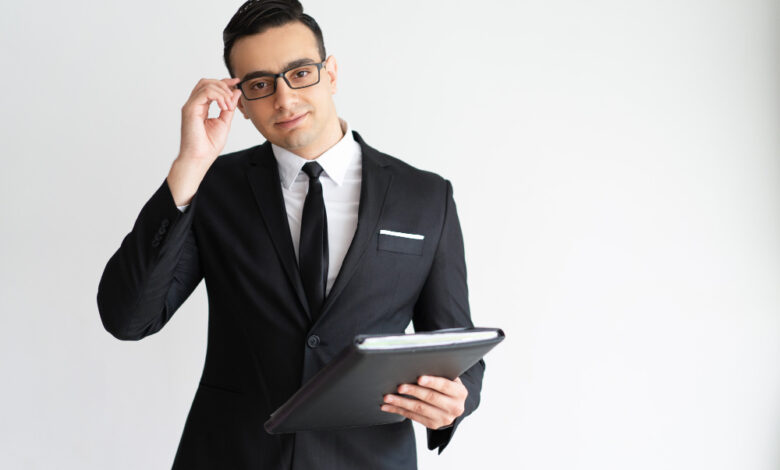 serious-handsome-young-businessman-adjusting-glasses-holding-folder